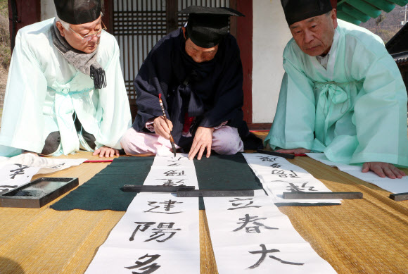 입춘(立春) 4일 오전 전북 전주시 완산구 전주향교에서 김춘원 전교(가운데)가 ‘입춘대길(立春大吉)’과 ‘건양다경(建陽多慶)’ 등 봄을 맞이하는 입춘방을 적고 있다. 연합뉴스