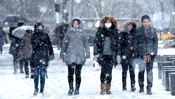 기습적인 폭설이 내린 16일 서울 광화문광장 인근에서 시민들이 눈을 맞으며 걷고 있다.  박지환기자 popocar@seoul.co.kr