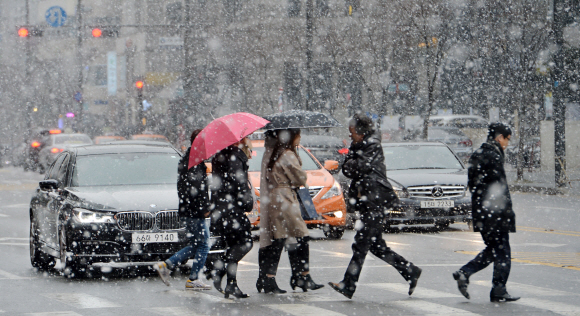 서울에 폭설이 내린 16일 서울 강남구 삼성동에서 우산을 쓴 시민들이 눈을 맞으며 횡단보도를 건너고 있다.  손형준 기자 boltagoo@seoul.co.kr