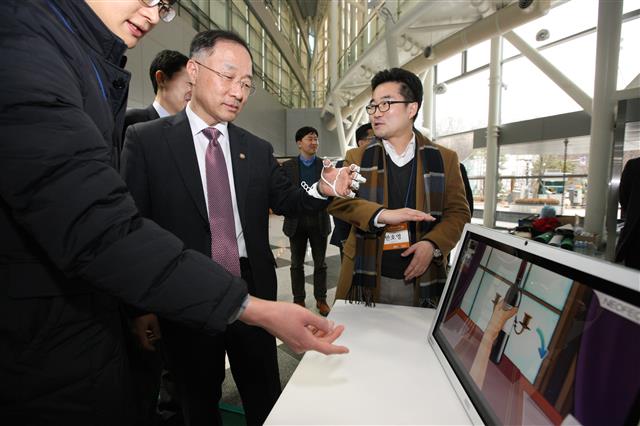 홍남기(왼쪽) 미래창조과학부 제1차관이 22일 ‘과기특성화대학 스타트업 채용 박람회’에 참석해 재활 게임을 해 보고 있다. 오른쪽은 디지털 재활 의료기기 개발 업체인 네오팩트의 반호영 대표. 미래창조과학부 제공