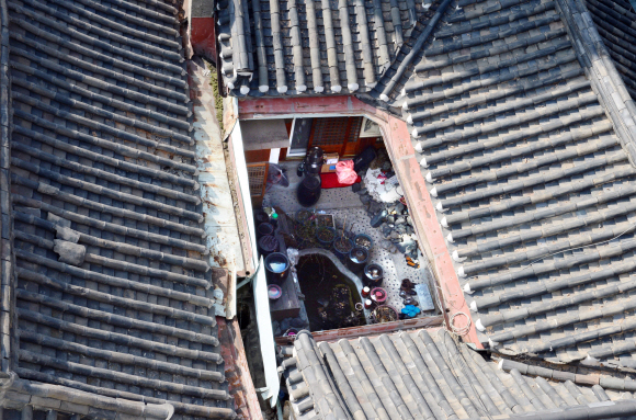 기와지붕 아래 놓여 있는 장독, 화분, 신발, 댓돌 등 세간살이들.