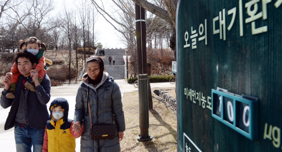 올봄 처음 황사주의보가 내려진 6일 성동구 서울숲 공원에 어린 자녀에게 마스크를 착용케하고 나들이 나온 가족이 미세먼지농도 표지판 옆을 지나고 있다.  2016.03.06 강성남 선임기자 snk@seoul.co.kr