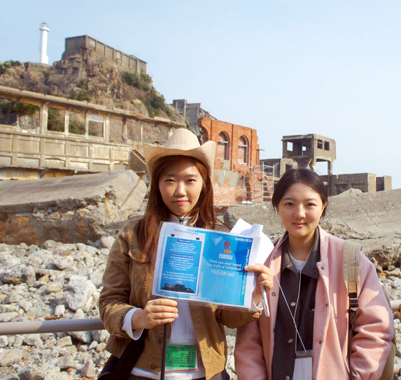 김영재(왼쪽)씨와 김윤경씨가 일본 하시마섬에서 이 섬이 일본 근대화의 상징이자 조선인 강제 노역의 현장이라는 내용을 담은 ‘두 섬 이야기’ 설명서를 들어 보이고 있다. 연합뉴스 