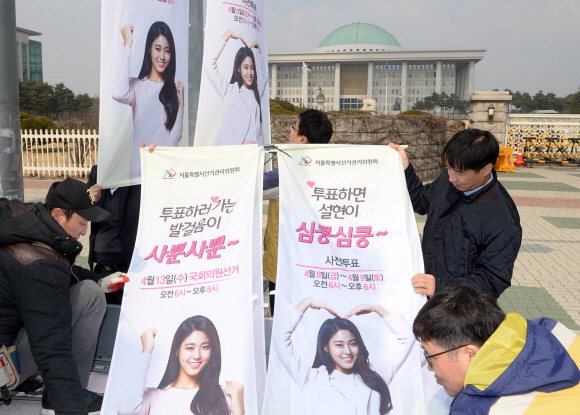 14일 서울 영등포구 여의도 국회 앞에서 서울시 선관위직원들이 선거를 독려하는 벽보를 붙이고 있다. 2016.3.14 박지환기자 popocar@seoul.co.kr