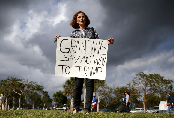 13일(현지시간) 미국 공화당 대선 후보 도널드 트럼프의 플로리다주 보카레이턴 유세장 밖에서 한 반대 시위자가 피켓을 들고 있다. AP 연합뉴스