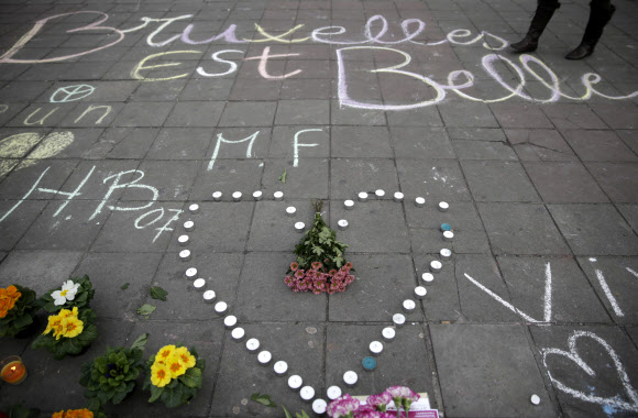 22일(현지시간) 벨기에 브뤼셀의 한 광장 시민들이 추모 글귀와 촛불·꽃다발을 바치며 희생자들을 추모하고 있다. AFP 연합뉴스