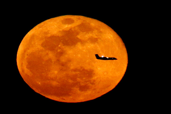 23일(현지시간) 비행기 한 대가 보름달을 지나 뉴어크 리버티 국제공항으로 향하는 모습이 미국 뉴저지 웨스트 오렌지의 이글 락 레저베이션에서 촬영됐다. AP 연합뉴스