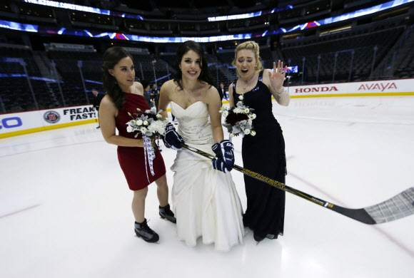 3일(현지시간) 미국 콜로라도주 덴버에서 북미아이스하키리그(NHL) 콜로라도 애벌랜치와 세인트루이스 블루스의 경기 시작되기 전 아이스링크에서 결혼식을 올린 한 신부와 들러리들이 기념사진을 찍고 있다. AP 연합뉴스