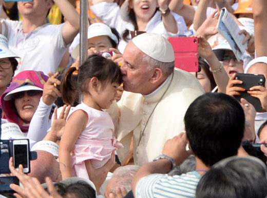 지난 2014년 8월 한국을 방문한 프란치스코 교황이 서울 광화문에서 집전한 한국 초기 순교자 124위에 대한 시복식에 앞서 카퍼레이드를 벌이던중 한 어린이의 이마에 축복 키스를 하고 있다. 서울신문 DB