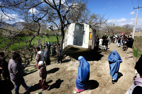 아프가니스탄 여성들이 지난 11일 수도 카불 근교에서 도로매설폭탄 폭발로 피해를 입은 버스 옆을 지나가고 있다. AP=연합뉴스
