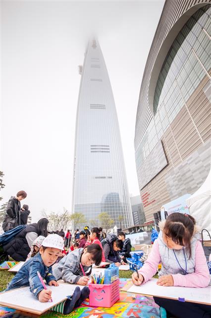 지난 9일 ‘제2회 롯데월드타워 어린이 그림대회’에 참가한 어린이들이 123층 높이의 롯데월드타워를 배경으로 그림을 그리고 있다.  롯데물산 제공