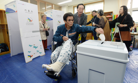제20대 국회의원 선거일인 13일 서울 종로구 경운동 경운학교에 마련된 종로 제2투표소에서 병원에 입원 중인 한 시민이 휠체어를 타고 와서 투표를 하고 있다.  손형준 기자 boltagoo@seoul.co.kr