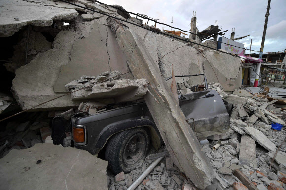 17일(현지시간) 에콰도르를 강타한 규모 7.8의 강진으로 붕괴된 지반 아래 묻힌 부서진 차량의 모습이 처참한 상황을 보여주고 있다.AFP 연합뉴스 
