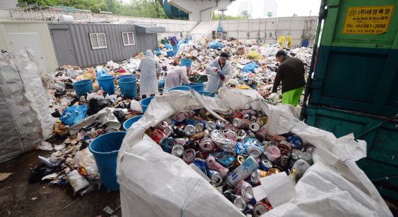 서울 영등포구 여의도 한강시민공원을 청소하는 환경미화원들이 10일 집하장에서 캔과 플라스틱 등 재활용이 가능한 쓰레기를 골라내고 있다.  손형준 기자 boltagoo@seoul.co.kr