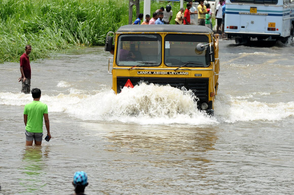 스리랑카에서 하루 최대 200?를 넘나드는 호우가 닷새째 계속되면서 홍수와 산사태로 18일(현지시간) 현재 35명이 사망하고 300여명이 실종됐다. 사진은 이날 수도 콜롬보 외곽에서 강으로 변한 도로를 차량들이 힘겹게 달리고 있는 모습. AP 연합뉴스