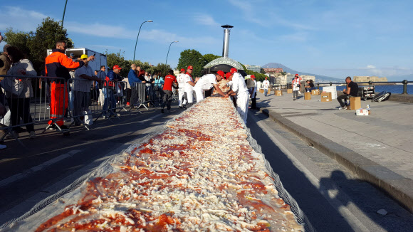 전 세계에서 모인 약 250여명의 피자 제작자들이 18일(현지시간) 남부 나폴리 해변에 보여 1.8㎞에 달하는 세계 최장 피자를 만들고있다.  AP 연합뉴스
