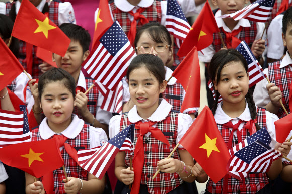 23일(현지시간) 버락 오바마 미국 대통령의 베트남 방문을 환영하기 위해 나온 어린이들이 미국 국기와 베트남 국기를 각각 손에 들고 흔들어 보이고 있다. AP 연합뉴스