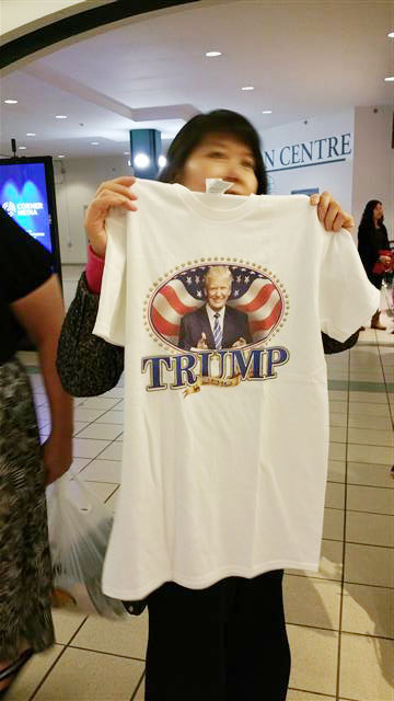 24일(현지시간) 미국 워싱턴DC 인근 버지니아주 펜타곤시티 쇼핑몰 내 상점 앞에서 만난 한 여성이 자신을 트럼프 지지자라고 밝히며 트럼프 얼굴 티셔츠를 들어 보이고 있다.