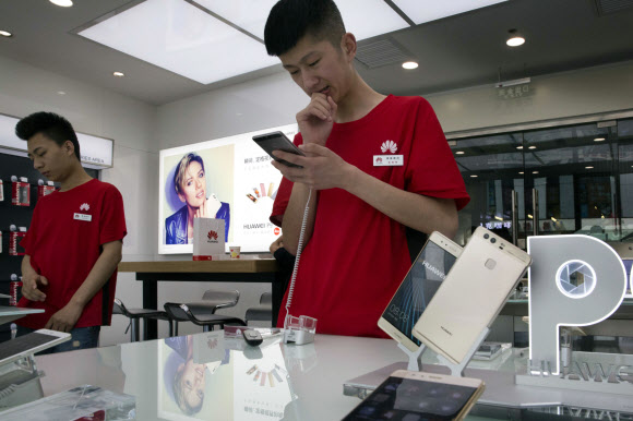 이달 초 중국 베이징에 있는 화웨이 스마트폰 대리점에서 판매 사원들이 제품을 들여다보고 있다. 베이징 AP 연합뉴스