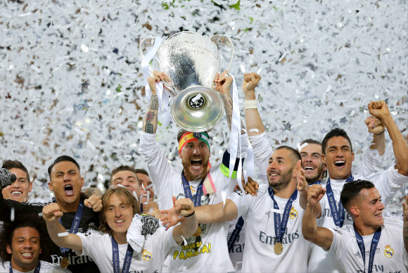 29일(현지시간) 이탈리아 밀라노의 산시로 스타디움에서 열린 2015-2016 유럽축구연맹(UEFA) 챔피언스리그 결승에서 아틀레티코 마드리드(스페인)를 꺾고 우승을 차지한 스페인 레알 마드리드의 세르히오 라모스(가운데)가 트로피를 높이 들고 동료들과 함께 환호하고 있다. 라모스는 이날 결승에서 선제골을 터뜨리고 승부차기에서도 골을 성공시켰다. AP 연합뉴스
