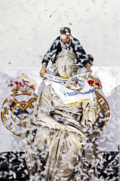 2015-2016 유럽축구연맹(UEFA) 챔피언스리그를 제패한 레알 마드리드 선수단은 29일(현지시간) 스페인 마드리드의 시벨레스 광장 분수대의 키벨레 여신 동상의 목에 구단 깃발을 감아주고 있다. AP 연합뉴스