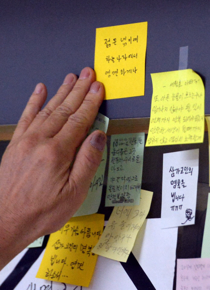 1일 서울 광진구 2호선 구의역 역무실 옆에 마련된 스크린도어 수리공 사망 사고 추모공간에 한 시민이 희생자를 추모하는 포스트잇을 붙이고 있다. 2016. 6. 1. 박윤슬 기자 seul@seoul.co.kr