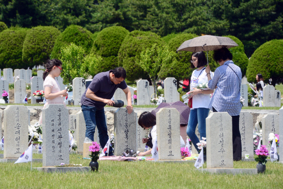 현충일을 하루 앞 둔 5일 서울 동작구 현충원을 찾은 한 참배객이 묘비를 닦고 있다.    정연호 기자 tpgod@seoul.co.kr