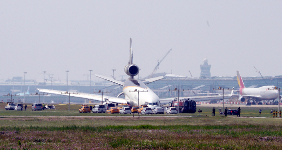 6일 오후 10시50분께 인천국제공항 1활주로에서 이륙 중 랜딩기어 고장으로 이륙하지 못하고 비상 착륙한 미국 국적의 UPS화물기 주변에 7일 오전 사고 수습을 위해 공항관계자와 소방당국이 작업을 하고 있다.  강성남 선임기자 snk@seoul.co.kr