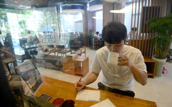 지난 10일 서울 용산구 우리은행 동부이촌동지점 카페 인 브랜치를 찾은 고객이 커피를 마시며 은행 일을 보고 있다. 박지환 기자 popocar@seoul.co.kr