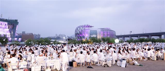 지난 11일 서울 반포지구 한강시민공원에서 열린 ‘디네앙블랑 서울’ 파티에 참가한 1000여명의 입장객이 흰색 드레스와 양복을 차려입고 반포 세빛섬을 배경으로 행사를 즐기고 있다.디네앙블랑 서울 제공