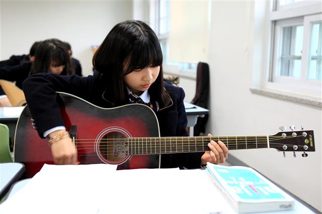 한 학생이 1인1기 시간에 기타를 연주하고 있다.