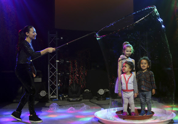 Melody Yang(왼쪽)이 7일(현지시간) 호주 시드니에서 열린 가질리언 버블쇼(Gazillion Bubble Show) 리허설에서 3명의 어린이 관객을 상대로 거대 버블 만들어 보이고 있다. AP 연합뉴스