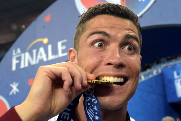 2016 유럽축구선수권대회에서 우승을 차지한 포르투갈의 크리스티아누 호날두가 금메달을 깨물어 보이며 익살스러운 표정을 짓고 있다.  EPA 연합뉴스