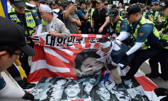 지난 12일 일본 자위대 창설 기념행사가 열린 서울 중구 남대문로 밀레니엄 힐튼호텔 앞에서 시민단체 회원들이 행사 개최에 반대하며 아베 신조 일본 총리의 얼굴이 새겨진 전범깃발(욱일기)을 찢고 있다. 서울신문 DB