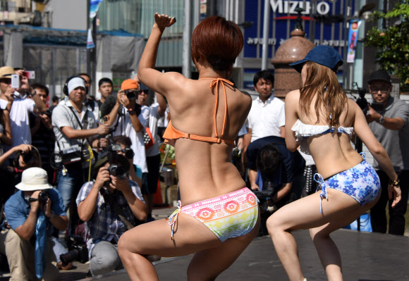 18일(현지시간) 일본 도쿄의 신주쿠역 앞 광장에서 비키니를 입은 여성들이 춤을 추며 플래시몹 이벤트를 하고 있다. AFP 연합뉴스