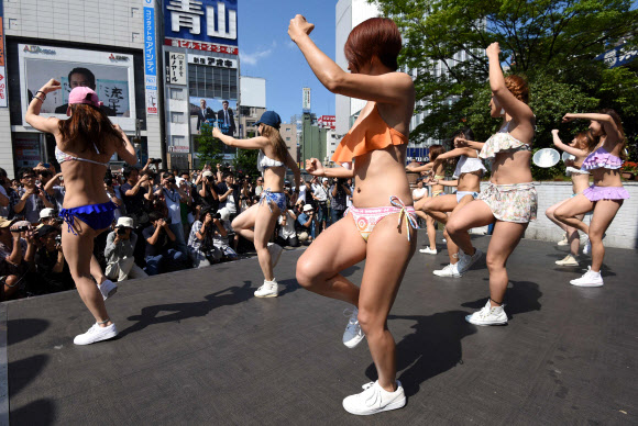 18일(현지시간) 일본 도쿄의 신주쿠역 앞 광장에서 비키니를 입은 여성들이 춤을 추며 플래시몹 이벤트를 하고 있다. AFP 연합뉴스