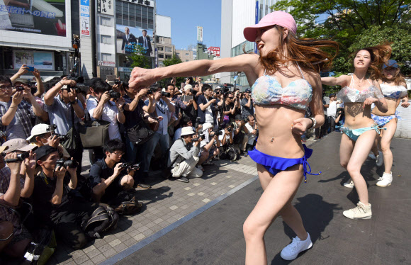 18일(현지시간) 일본 도쿄의 신주쿠역 앞 광장에서 비키니를 입은 여성들이 춤을 추며 플래시몹 이벤트를 하고 있다. AFP 연합뉴스