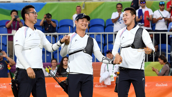 6일 (현지시각) 브라질 리우 마라카낭 삼보드로무 양궁경기장에서 열린 리우 올림픽 남자 양궁단제전 에서 대한민국 남자 양궁팀의 금매달이 확정되자 김우진,이승윤,구본찬 선수가  손을 잡고 환호하고 있다. 리우데자네이루=올림픽사진공동취재단