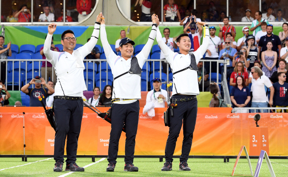 6일 (현지시각) 브라질 리우 마라카낭 삼보드로무 양궁경기장에서 열린 리우 올림픽 남자 양궁단제전 에서 대한민국 남자 양궁팀의 금매달이 확정되자 김우진,이승윤,구본찬 선수가  손을 잡고 환호하고 있다. 리우데자네이루=올림픽사진공동취재단