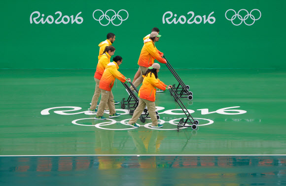자원봉사자들이 10일(현지시간) 리우올림픽 테니스 경기가 열리는 센트럴 코트에 고인 물을 제거하느라 작업에 열중하고 있다.  리우데자네이루 AP 연합뉴스 