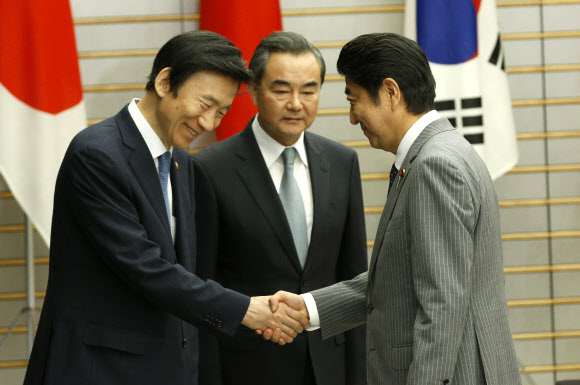 24일 한·중·일 외교장관회의 참석차 일본을 방문 중인 윤병세(왼쪽) 외교부 장관이 왕이(가운데) 중국 외교부장과 함께 도쿄 총리 공관에서 아베 신조 일본 총리를 예방하며 악수를 나누고 있다. 도쿄 AFP 연합뉴스