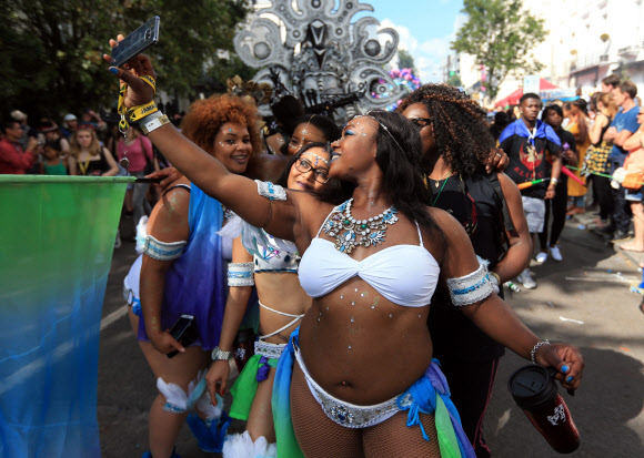 29일(현지시간) 영국 런던에서 열린 노팅힐 카니발 퍼레이드에 참가한 댄서들이 기념 셀카를 찍고 있다. AP 연합뉴스