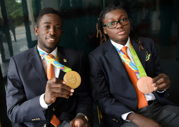 리우올림픽 태권도 남자 80kg급 결승에서 극적인 역전승을 거두고 코트디부아르 최초의 올림픽 금메달리스트가 된 셰이크 살라 시세(왼쪽)가 5일 수도 아비장의 대통령궁에서 열린 환영식 도중 목에 건 금메달을 내보이고 있다. 오른쪽은 여자 67kg급에서 코트디부아르 최초의 여성 (동)메달리스트로 이름을 올린 루스 그바그비. AP 연합뉴스