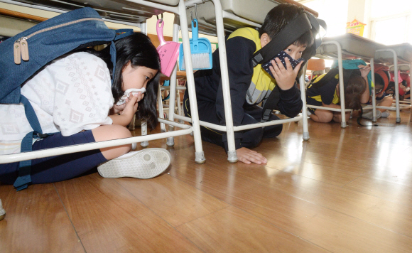 23일 오전 서울 강북구 송중초등학교에서 지진대피 훈련이 실시되고 있다. 지진경보가 울리자 학생들이 신속하게 책상 밑으로 몸을 숨기고 있다.   이언탁 기자 utl@seoul.co.kr
