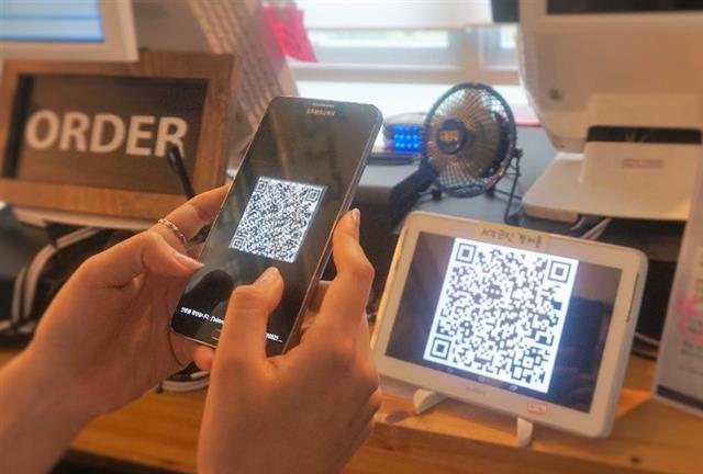 지난달 서울 마포구 서강대 교내 카페에서 열린 ‘가상화폐 서강코인 시연회’에서 한 학생이 스마트폰에 설치한 서강코인 앱으로 결제를 하고 있다. 더루프 제공