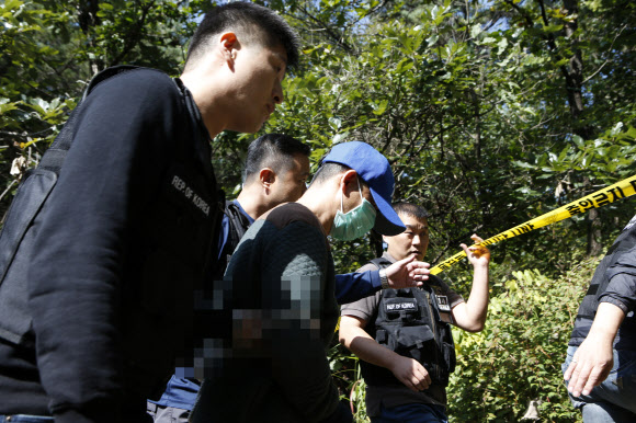 입양한 6세 딸을 살해한 혐의를 받고 있는 주모(가운데)씨가 3일 경기도 포천의 한 야산에서 현장조사를 받고 있다. 연합뉴스