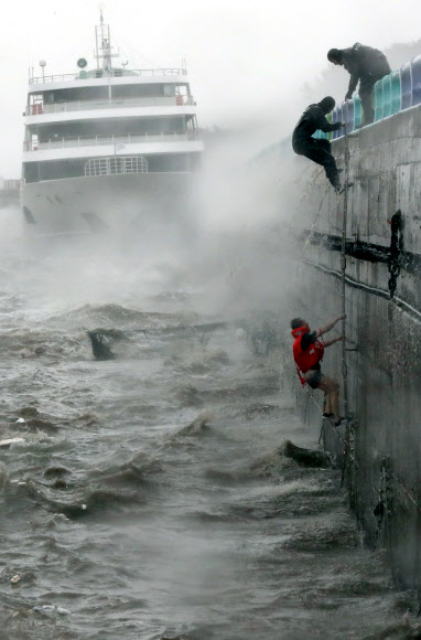 제18호 태풍 ’차바’가 북상한 5일 오전 전남 여수시 오동도 방파제에 여객선이 좌초해 물에 빠진 선원을 해경이 구조하고 있다.  연합뉴스