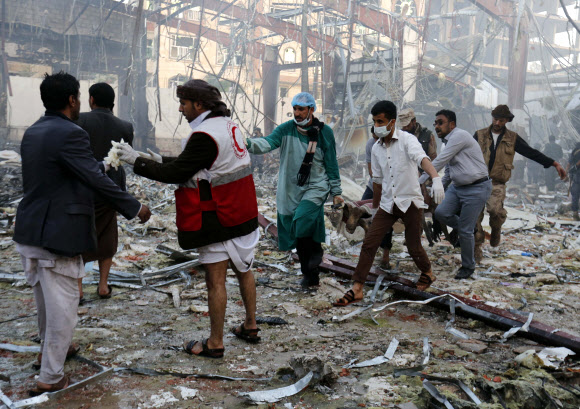 사우디아라비아 주도 동맹군이 8일(현지시간) 예멘 수도 사나에서 열린 반군 유력 인사의 장례식장을 폭격해 대규모 인명피해가 난 가운데 의료진이 희생자들을 옮기고 있다. 이번 폭격으로 최소 155명이 사망했으며 500여명이 다쳤다고 현지 관리들이 전했다. AP 연합뉴스