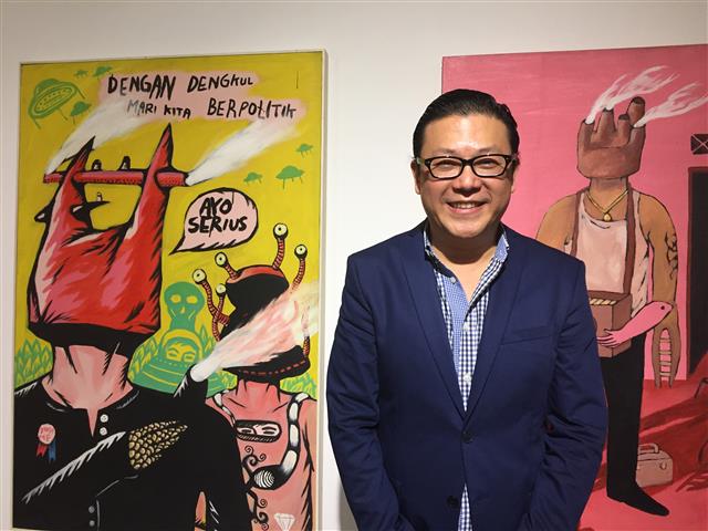 인도네시아 현대미술의 후원자이자 예술가들의 친구인 톰 탄디오가 에코 네그로호의 작품 앞에서 웃고 있다.