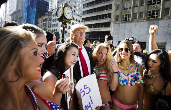 25일(현지시간) 미국 뉴욕의 트럼프 타워 앞에서 미국 공화당 대선후보 도널드 트럼프 분장을 한 가짜 도널드 트럼프와 비키니를 입은 여성들이 논란이 되고 있는 트럼프의 ‘성추문’ 풍자 퍼포먼스를 선보이고 있다. EPA 연합뉴스